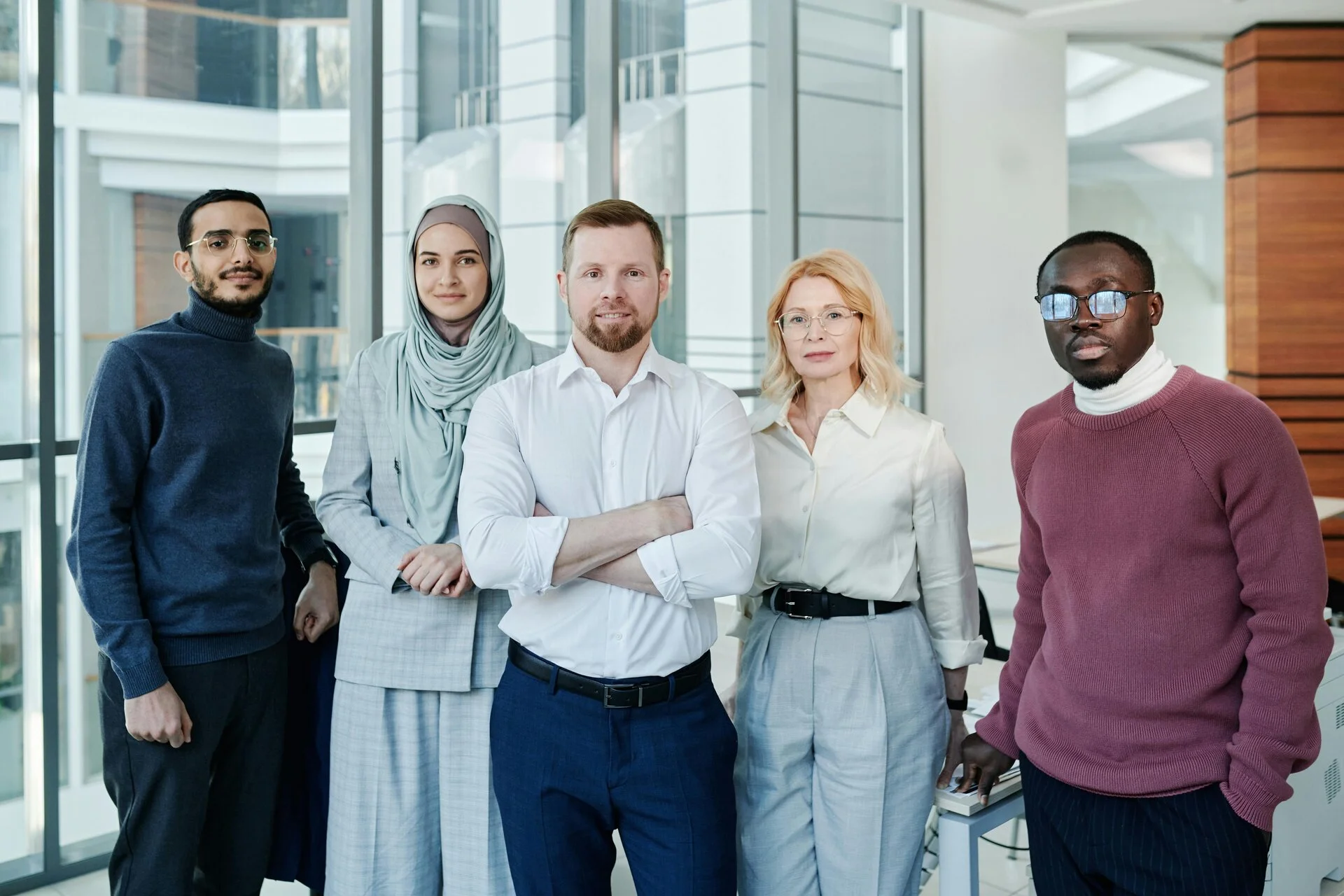 Multiple people standing together in a office building all people are from different countries, making it happen that the company have natives speaking there language while doing business